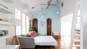 A bedroom with a bed, a desk, a lamp, a chair, and a plant.