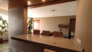 Una cocina con encimera de granito, un refrigerador y varias plantas en macetas.