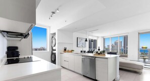 A modern kitchen with a central island, built-in appliances, and large windows offering city views.