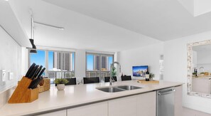 A modern kitchen with a large island, stainless steel appliances, and a view of tall buildings.