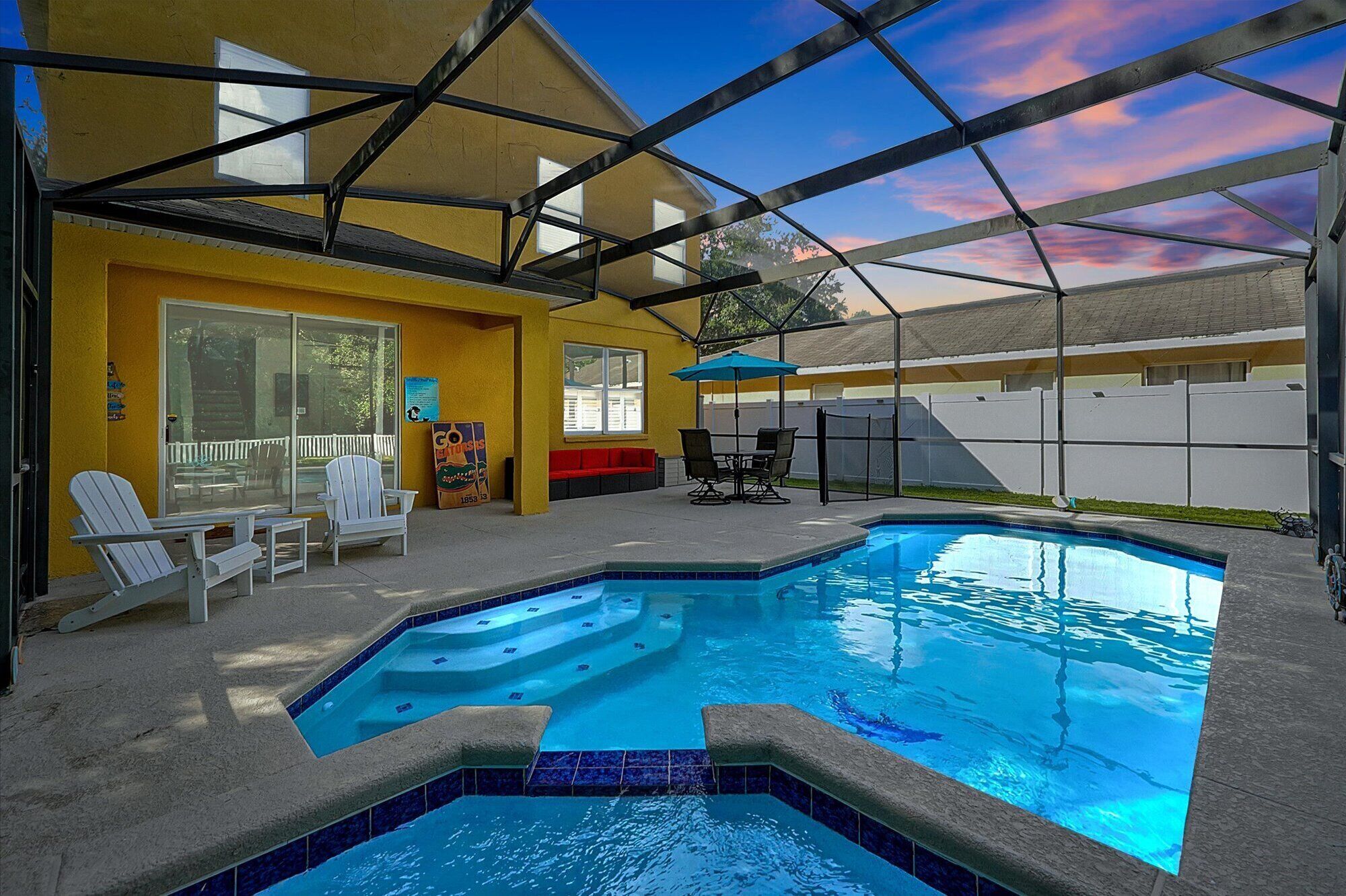 Una piscina interior amb sostre de vidre, envoltada per un edifici groc amb una banca vermella i una taula amb caires.