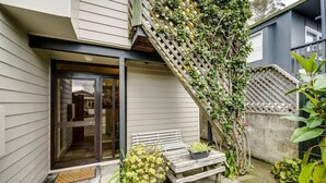 A residential property with a wooden bench, potted plants, and a staircase leading to a second floor.