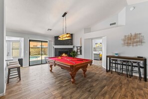 Amplia sala de estar con mesa de billar, chimenea y barra.