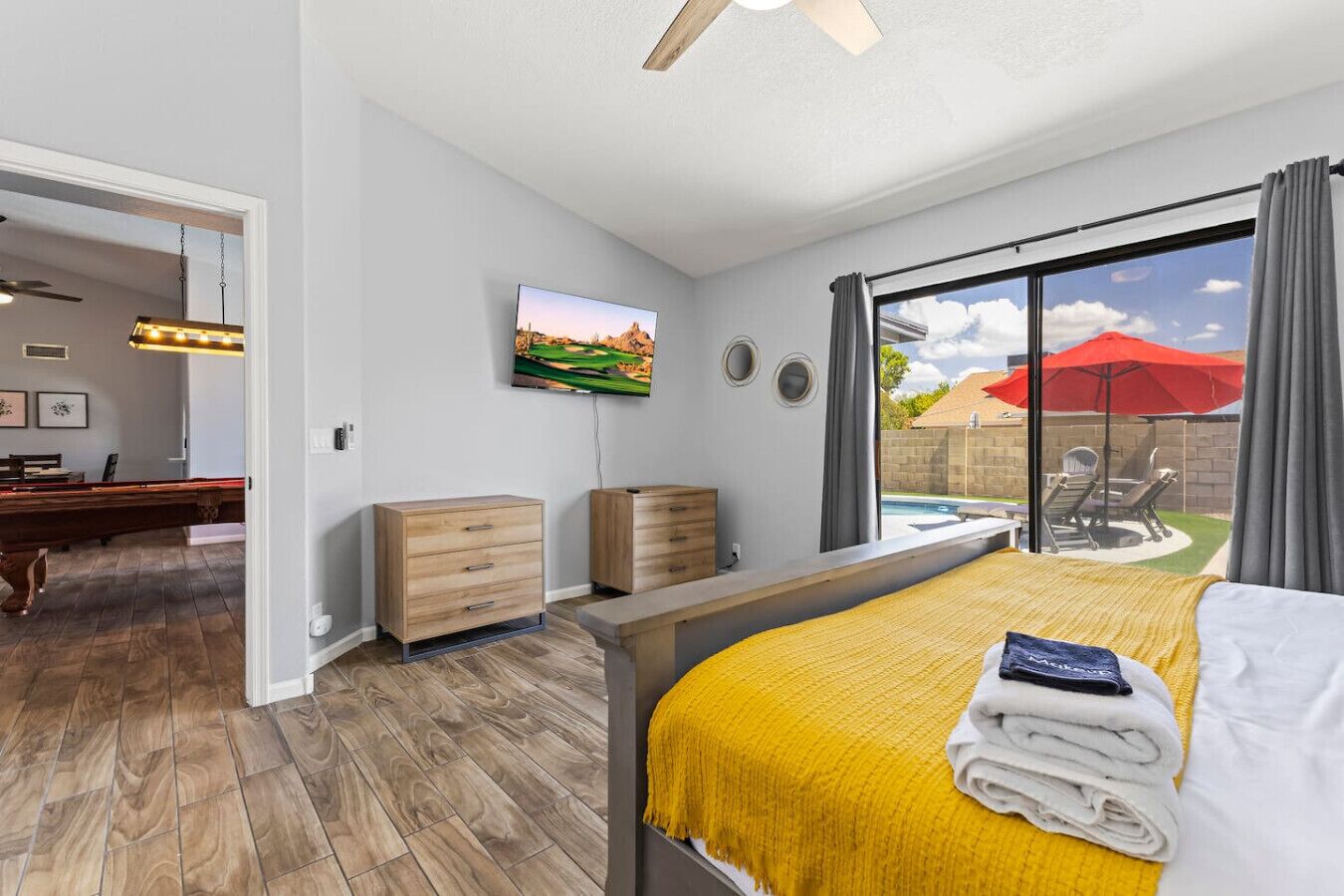 A bedroom with a bed, a TV, a pool view, and a ceiling fan.