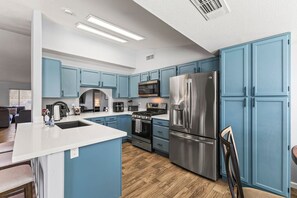 A modern kitchen with blue cabinets, stainless steel appliances, and a central island. - Walk To The Stadium with Pool, Putting Green, & Pool Table & Great Location (Glendale)