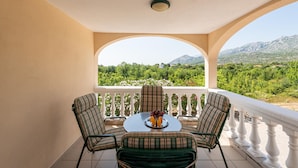 A balcony with a table and chairs, a view of a mountainous landscape, and a ceiling light. - 1 bedroom awesome apartment in Seline (Seline)