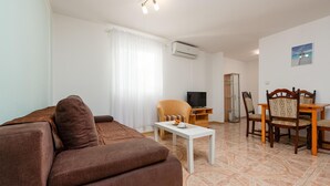 A living room with a brown sofa, a white coffee table, a TV, a dining table with chairs, and a cabinet. - 1 bedroom awesome apartment in Seline (Seline)