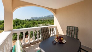 A balcony with a table and chairs, a view of greenery and mountains, and a clear sky. - Nice apartment in Seline with WiFi (Seline)