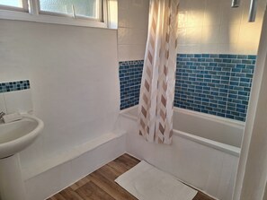 A bathroom with a white sink, a bathtub, and a shower curtain. - Country Cottage Retreat in Huntingdon (Huntingdon)