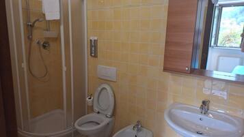 Un baño con ducha, inodoro, bidé y lavamanos.