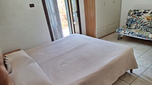 Une chambre à coucher comprenant un lit, une armoire et un banc orné d’un motif floral.