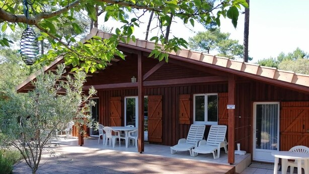 Une cabane en bois dotée d’un patio couvert, de meubles d’extérieur et d’un panneau indiquant que la ville la plus proche se trouve à 10 minutes en voiture.