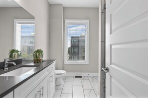 Een moderne badkamer met een groot wastafel, toilet en raam.
