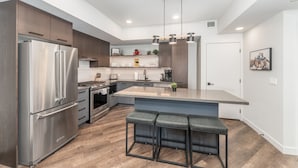 A modern kitchen with stainless steel appliances, a central island with bar stools, and a pendant light fixture. - 1,250 SF Luxury Home | 4-BR + 3-BA & 8 Beds | Best Amenities in Canmore (Canmore)