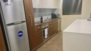 A kitchen with a stainless steel refrigerator, wooden cabinets, a built-in oven, and a white countertop. - Absollut 9 - Central location (Mount Hotham)