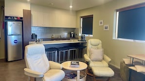 A modern kitchen with white cabinets, a stainless steel refrigerator, and a dining area with two white leather chairs and a small round table. - Absollut 9 - Central location (Mount Hotham)