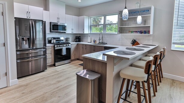 Una cocina moderna con electrodomésticos de acero inoxidable, una isla central con taburetes altos y un ventanal que proporciona luz natural.