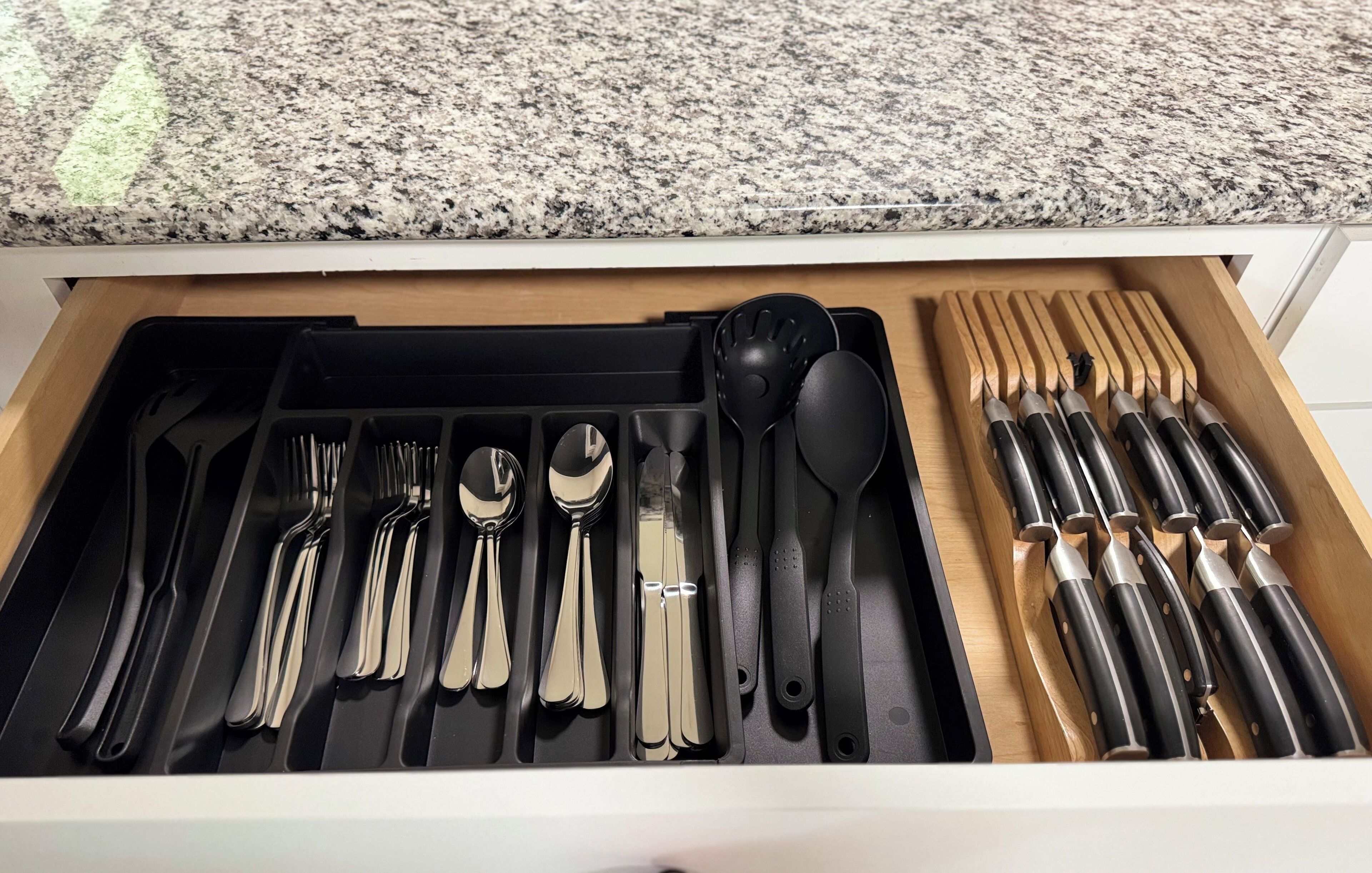 Un cassetto con utensili da cucina ordinati, tra cui forchette, cucchiai e coltelli.
