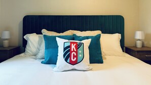 Ein Hotelzimmer mit Bett, Kissen und einem Wandschild mit der Aufschrift 'Kansas City'.