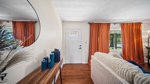 Ein Zimmer mit einem hölzernen Schminktisch, einem weißen Sofa und orangefarbenen Vorhängen.