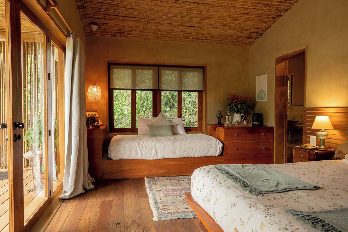 A bedroom with a wooden bed, a nightstand, a dresser, and a window with curtains.