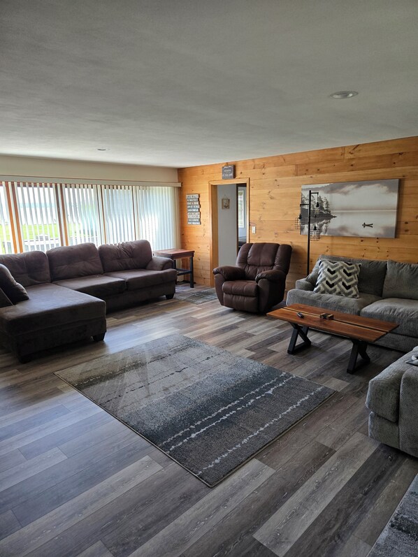 A living room with a sectional sofa, a recliner, a coffee table, and a painting on the wall.