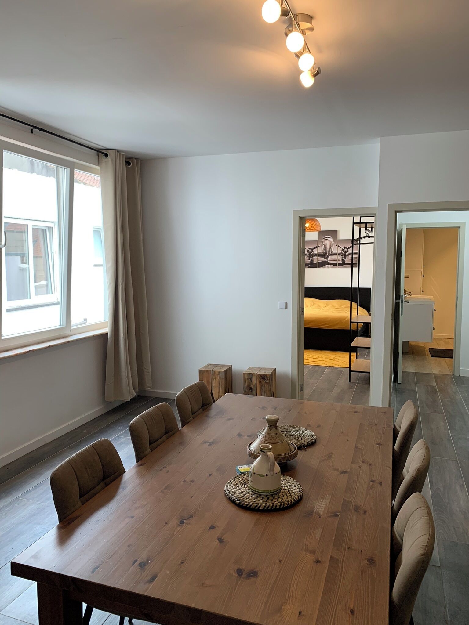 Un comedor moderno con una mesa de madera, seis sillas y un centro decorativo.