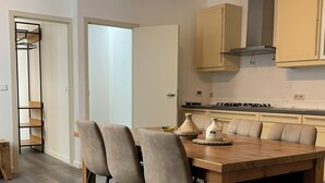 A modern kitchen with a dining table, chairs, and cabinets. - Soothing 7-bedroom house with WiFi in Ronse. (Ronse)