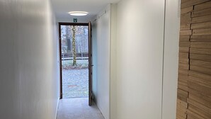 A narrow hallway with white walls and a wooden panel on one side. - Soothing 7-bedroom house with WiFi in Ronse. (Ronse)
