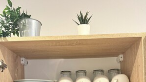Une étagère en bois contenant des ustensiles de cuisine et des plantes.