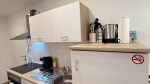 Une cuisine compacte dotée d’une cuisinière intégrée, d’un évier et de placards de rangement.