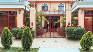 A two-story house with a gated entrance, a number '37' on the gate, and a well-maintained garden with trimmed bushes and trees. - Brisas del Aeropuerto (La Asunción)
