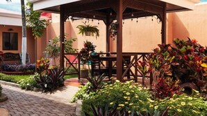 A covered outdoor seating area with a wooden structure, surrounded by potted plants and flowers. - Brisas del Aeropuerto (La Asunción)