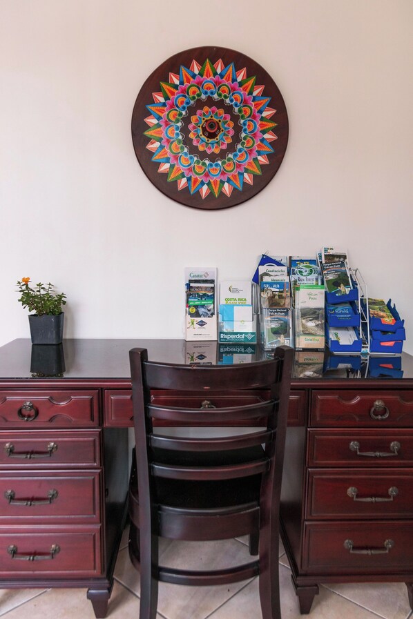 A wooden desk with a chair, a potted plant, and a colorful wall decoration. - Brisas del Aeropuerto (La Asunción)