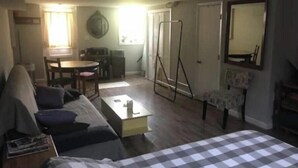 Ein gemütlicher Wohnbereich mit Sofa, Esstisch, Couchtisch, Spiegel und Kleiderschrank.