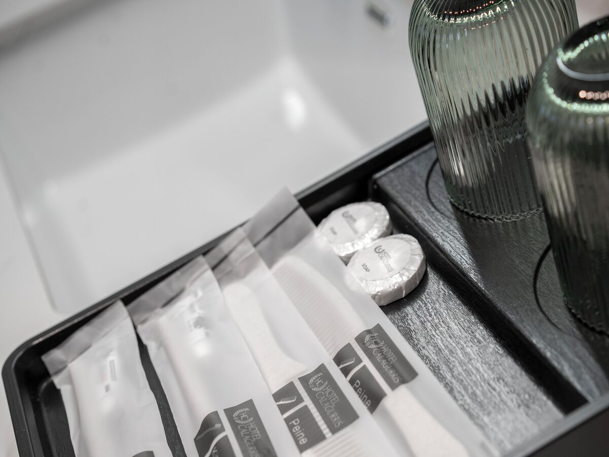 Una habitación de hotel con cama, mesita de noche y espejo.