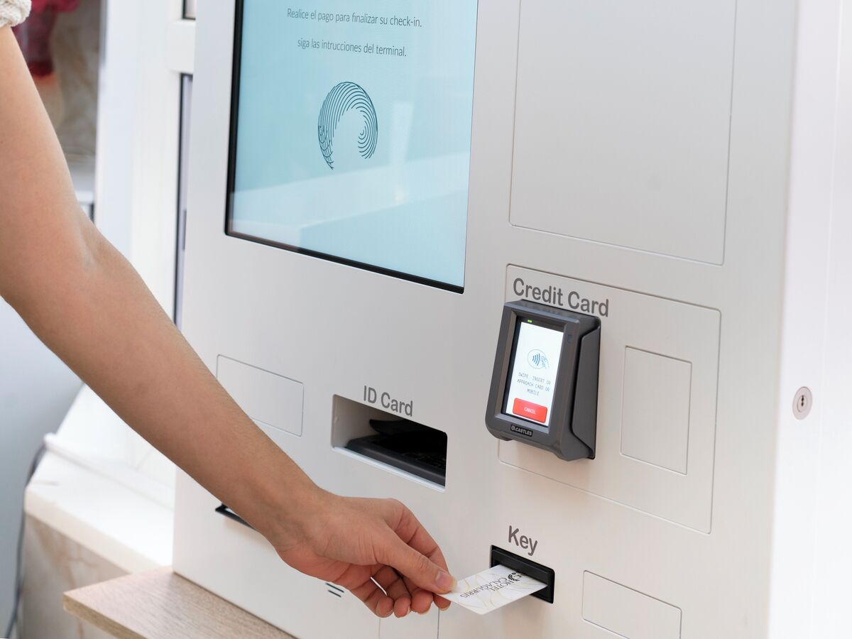 Une personne utilisant un terminal de paiement doté d’un lecteur de carte d’identité et d’un lecteur de carte de crédit.
