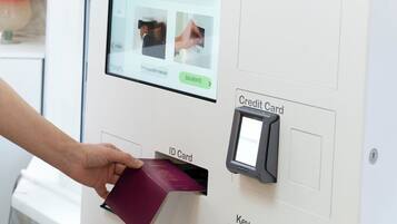 A person inserting an ID card into a machine with a screen displaying instructions.