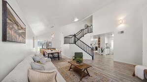 Ein großzügiger Wohnbereich mit Treppe, einer Sofagarnitur, einem Couchtisch und einem Essbereich.