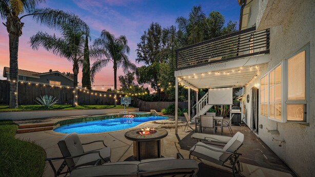 Ein Garten mit Swimmingpool, Terrassenmöbeln und Lichterketten.