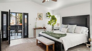 Ein Schlafzimmer mit Bett, Sitzbank, Deckenventilator, Tür und Fenster.