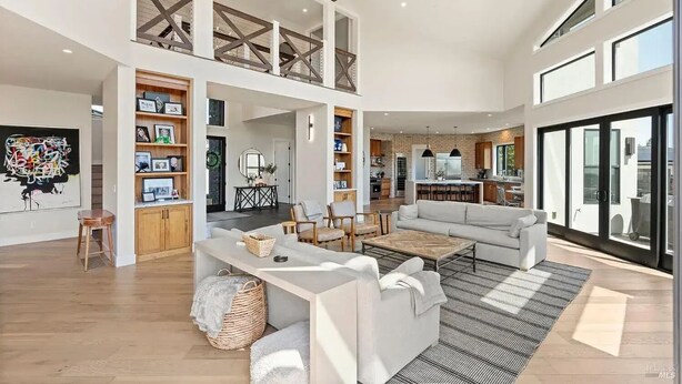 A spacious living area with a high ceiling, a kitchen, and a dining area.