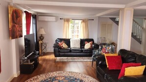 A living room with a black leather sofa, a TV, a lamp, and a patterned rug. - Home in Carellie Gardens (Bisee)