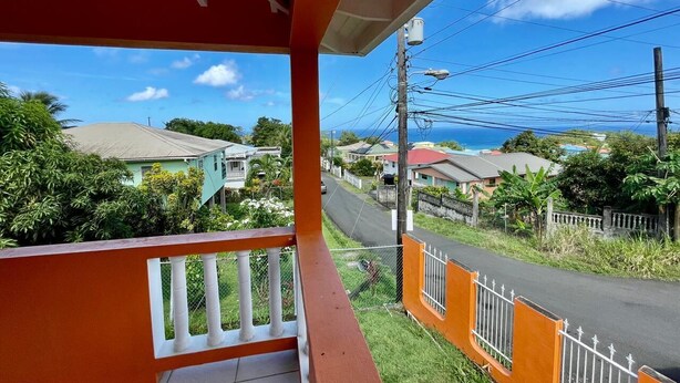 A residential street with houses, a clear sky, and a view of the ocean. - Home in Carellie Gardens (Bisee)