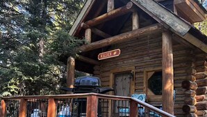 A rustic log cabin with a wooden deck and a sign that reads "WALDEN". - Walden Cabin Yellowstone (Silver Gate)