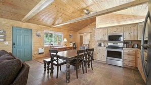 A log cabin interior with a dining area, kitchen, and a blue door. - Stunning Log Cabin Close to Panguitch Lake (Panguitch)