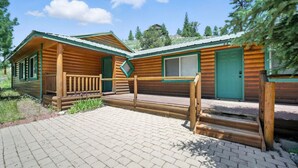 A rustic cabin with a wooden exterior, a porch, and a green door. - Stunning Log Cabin Close to Panguitch Lake (Panguitch)