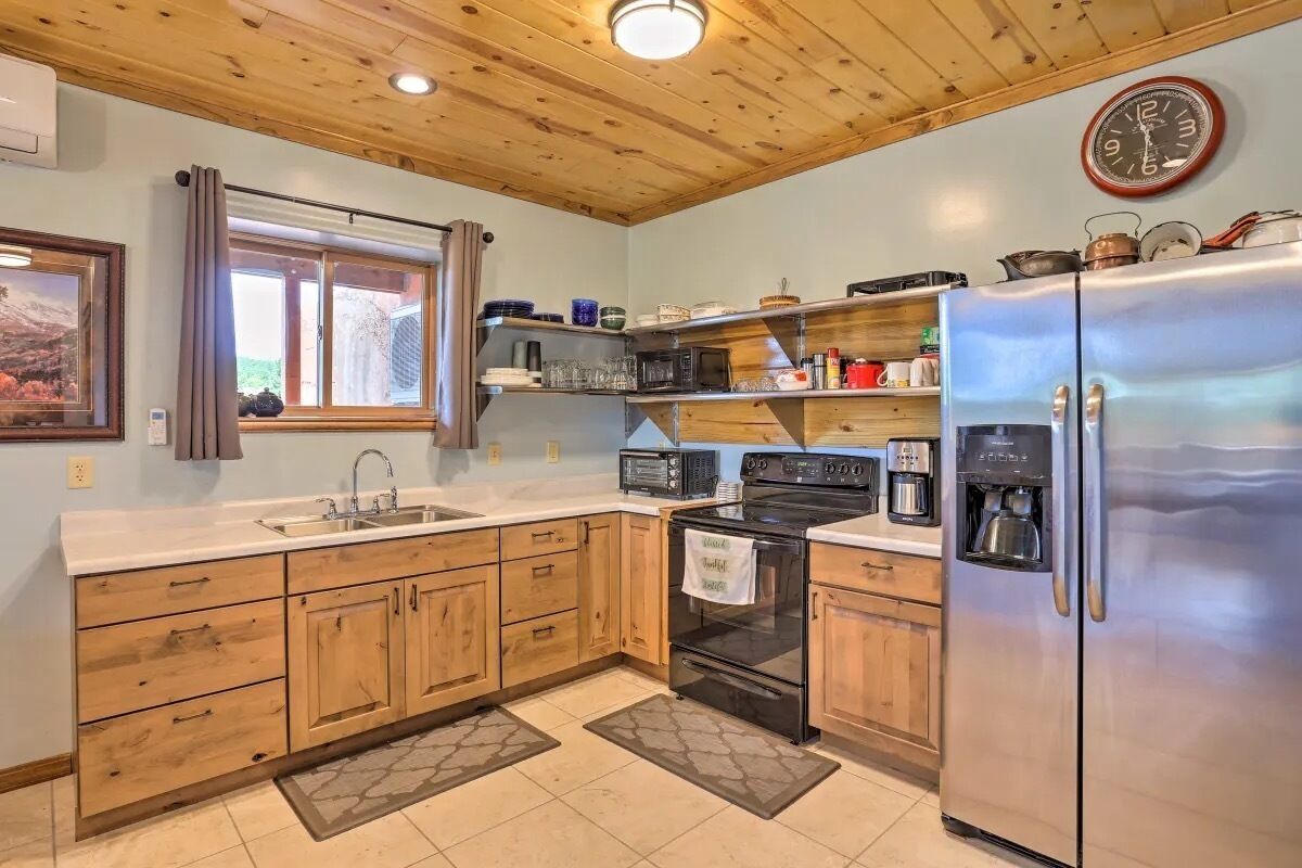 A kitchen with wooden cabinets, a stainless steel refrigerator, a microwave, and a stove.