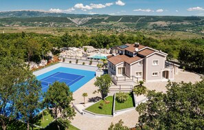 A large house with a tennis court and a swimming pool, surrounded by lush greenery and mountains in the background. - Luxurious home in Poljica with sauna (Poljica)