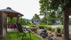A gazebo with outdoor seating, a well-maintained lawn, and a stone retaining wall. - Okanagan Escape (Kelowna)